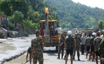 Security personnel and rescue workers clear flood debris during Bhotekoshi flood relief operations in Nepal