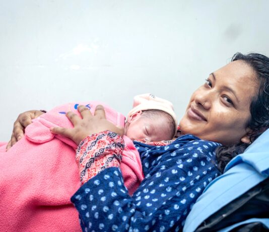 नेपालमा नवजात शिशुलाई काखमा राखेकी आमा