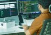 A person working at two computer monitors, representing AI agent operations and IT systems.
