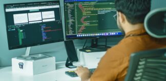 A person working at two computer monitors, representing AI agent operations and IT systems.