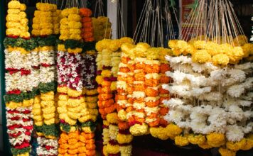 छ कठ्ठामा १० हजार सयपत्री, तिहारमा तीन लाख रुपैयाँ आम्दानीको अपेक्षा Orange marigold garlands hanging at a roadside flower shop; representative image for Nepal's Tihar flower market, not a photograph of the specific affected farms.
