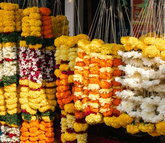 Orange marigold garlands hanging at a roadside flower shop; representative image for Nepal's Tihar flower market, not a photograph of the specific affected farms.