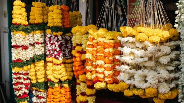 Orange marigold garlands hanging at a roadside flower shop; representative image for Nepal's Tihar flower market, not a photograph of the specific affected farms.